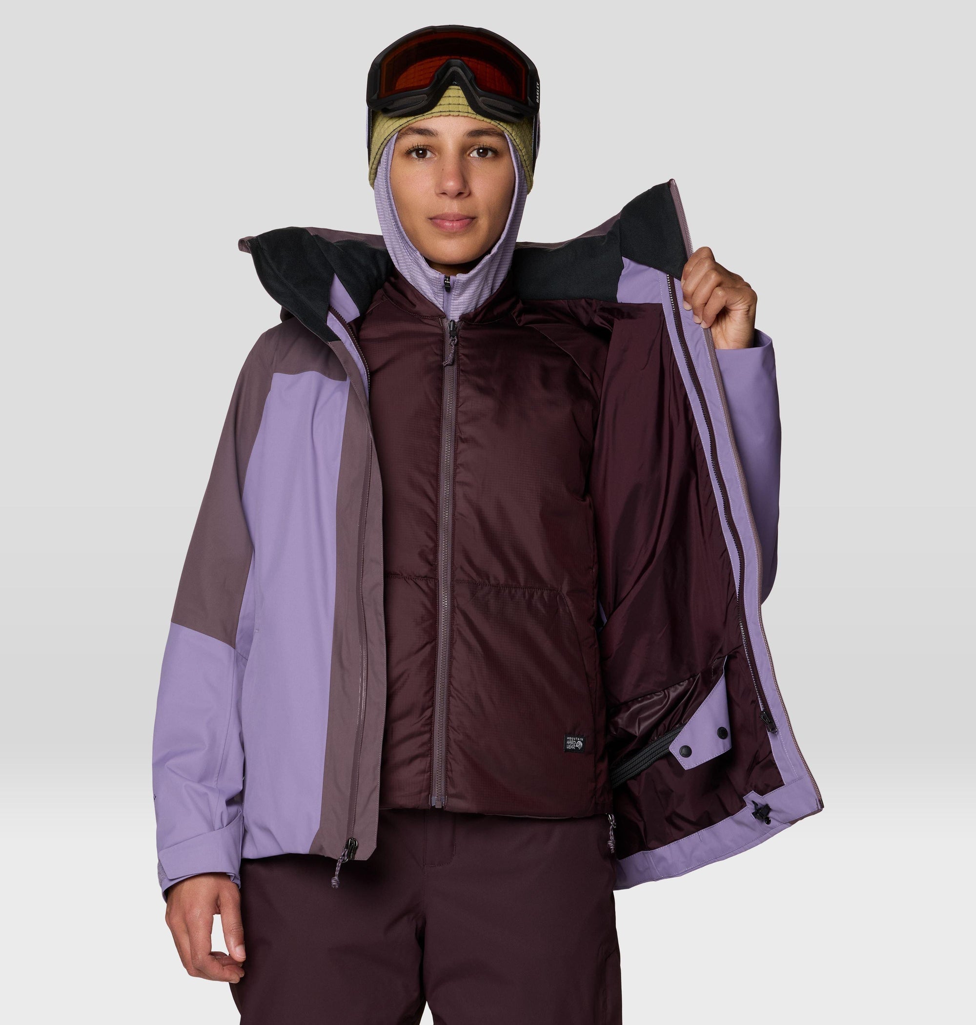 Women's trifecta ski jacket shown open, revealing insulated inner vest, colorblock purple design
