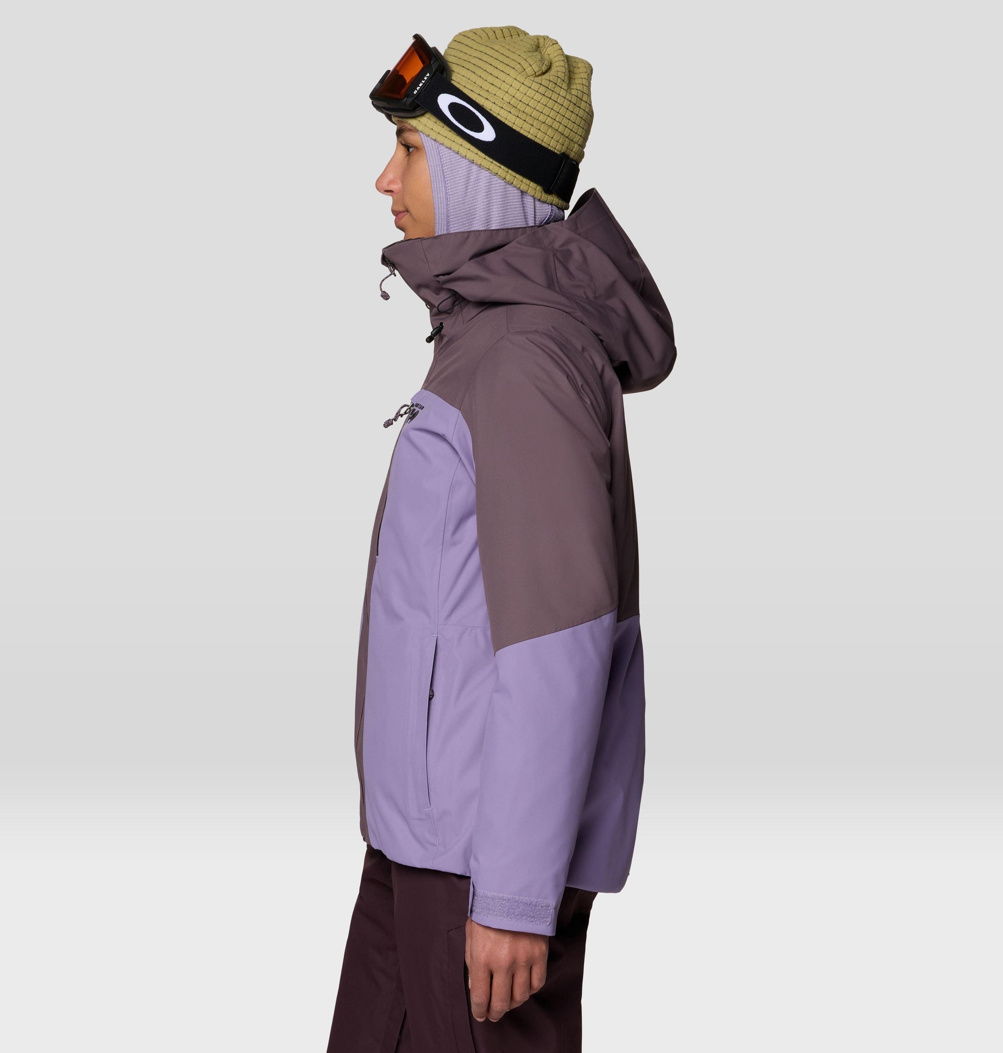 Women's ski jacket in colorblock purple tones, side view, with hood and goggles