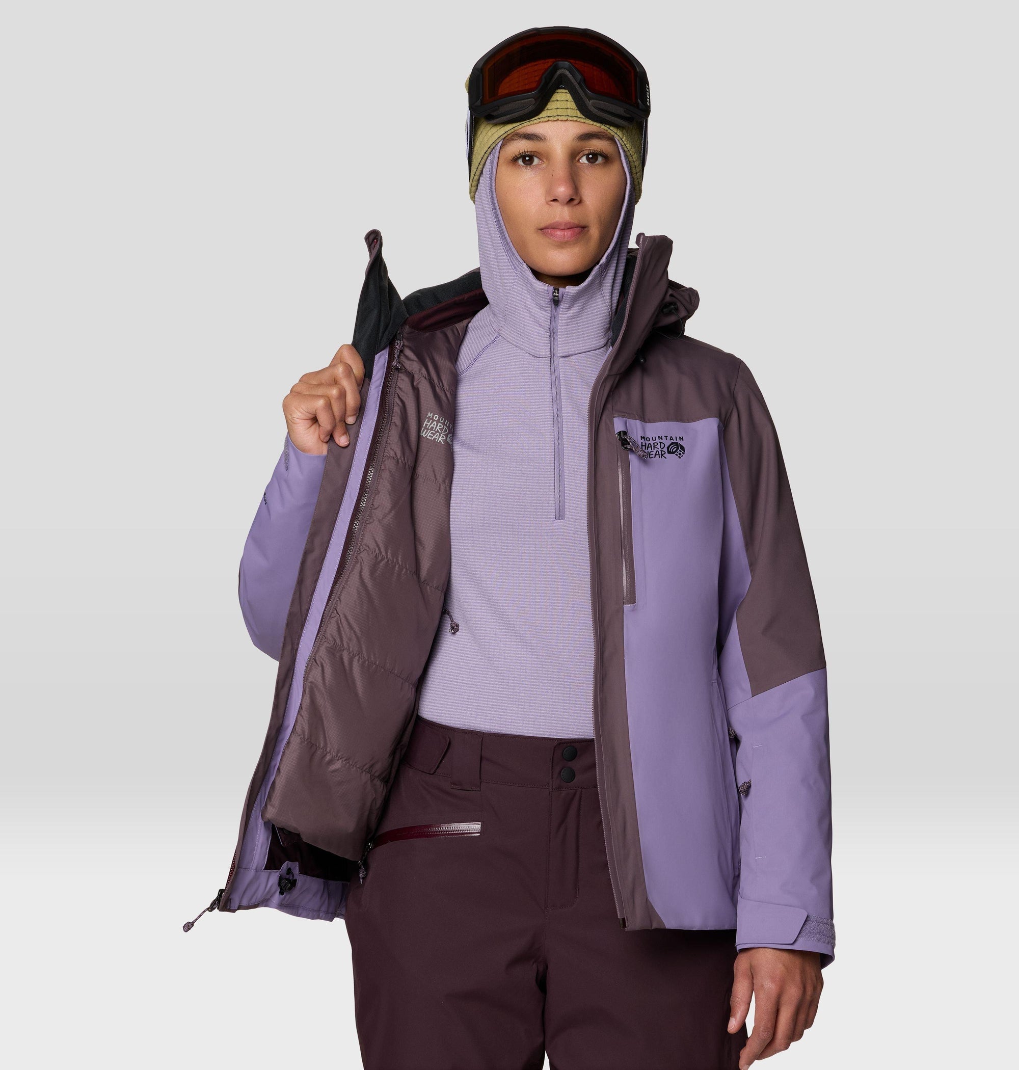 Women's ski jacket open to show insulated interior, worn with goggles and fleece midlayer