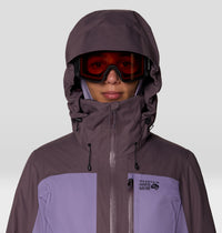 Women's ski jacket with helmet-compatible hood, adjustable collar, and two-tone purple colorblock design, close-up front view