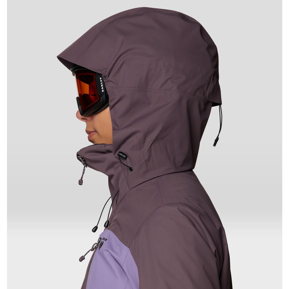 Close-up side view of hooded ski jacket with ski goggles, showing helmet-compatible hood and adjustable drawcords