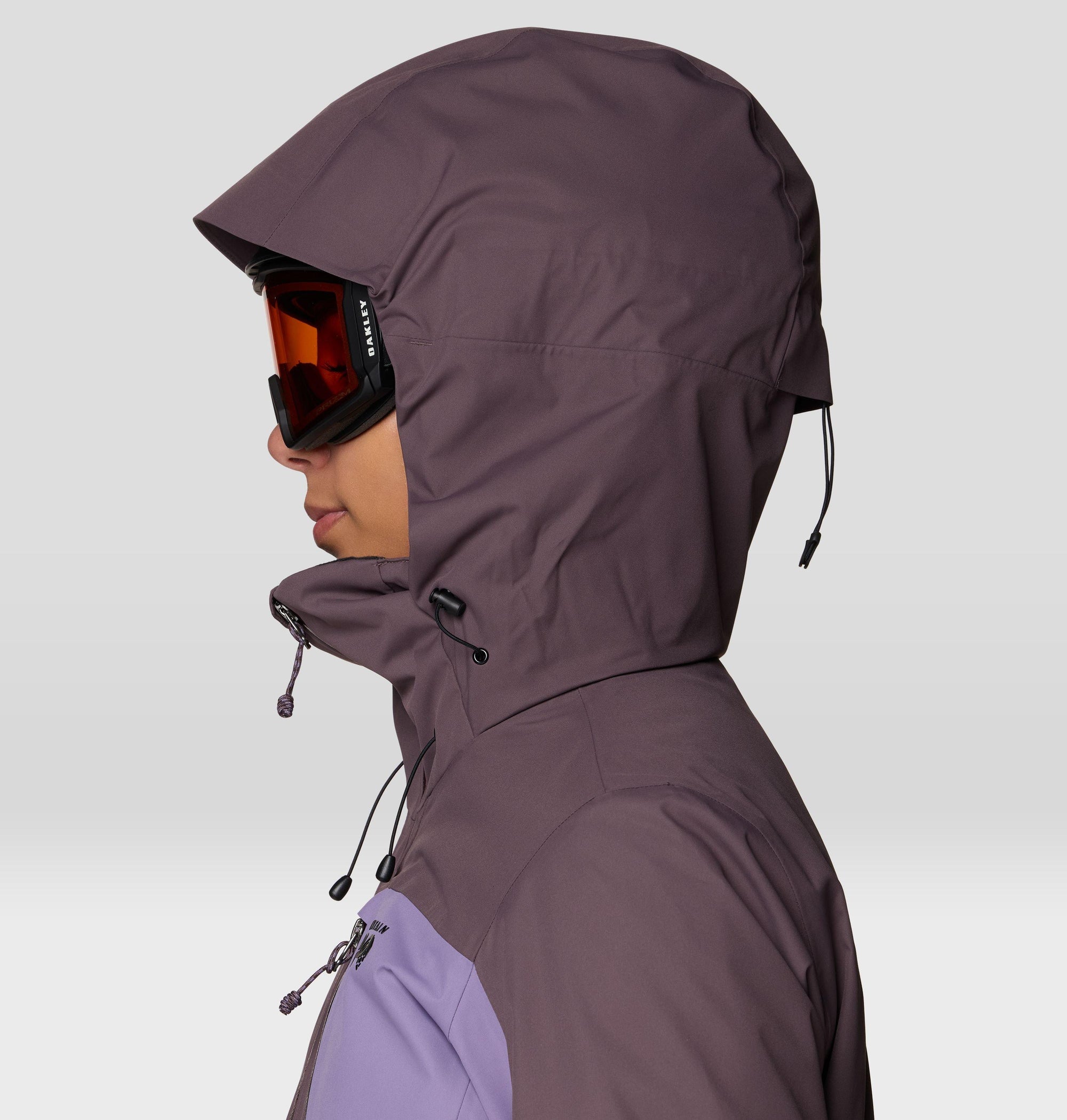 Women's ski jacket hood close-up with helmet-compatible fit and orange snow goggles, side view