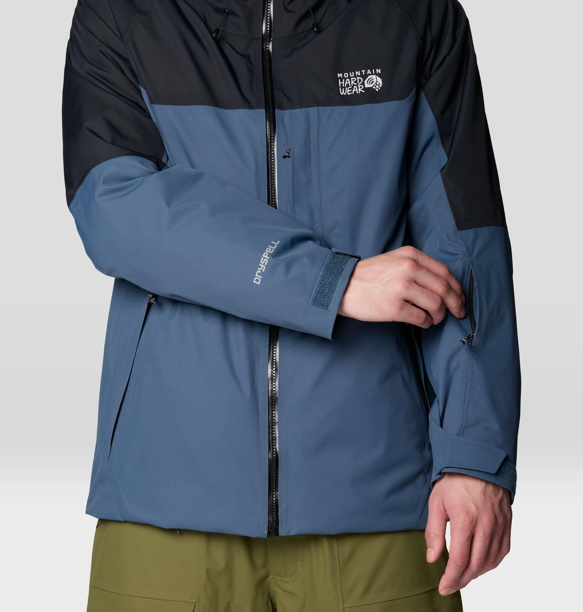 Two-tone waterproof hardshell jacket with black upper and blue lower, close-up front view showing zipper and cuffs