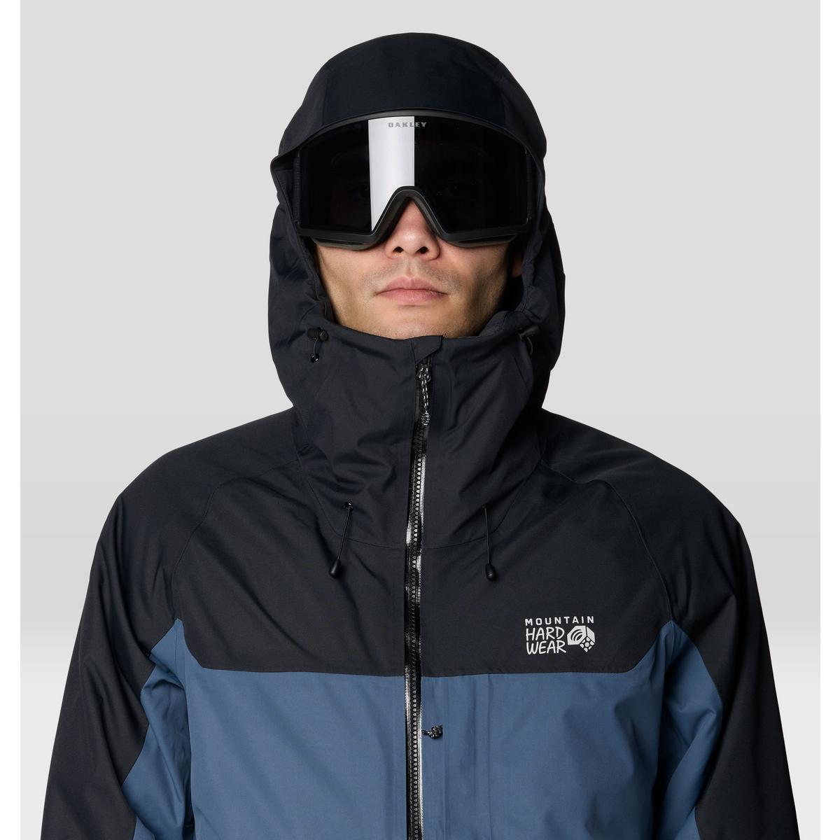 Men's hooded ski jacket with black upper and blue lower panel, worn with ski goggles