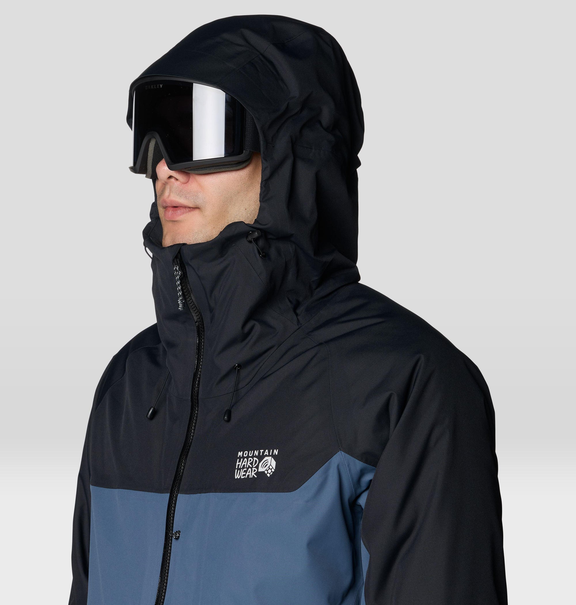 Men's hooded ski jacket close-up with goggles, two-tone blue and black colorblock design