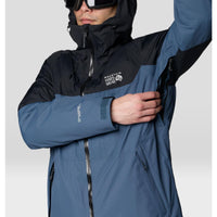 Men's ski jacket with blue and black colorblock panels, hood up, arm raised showing underarm detail