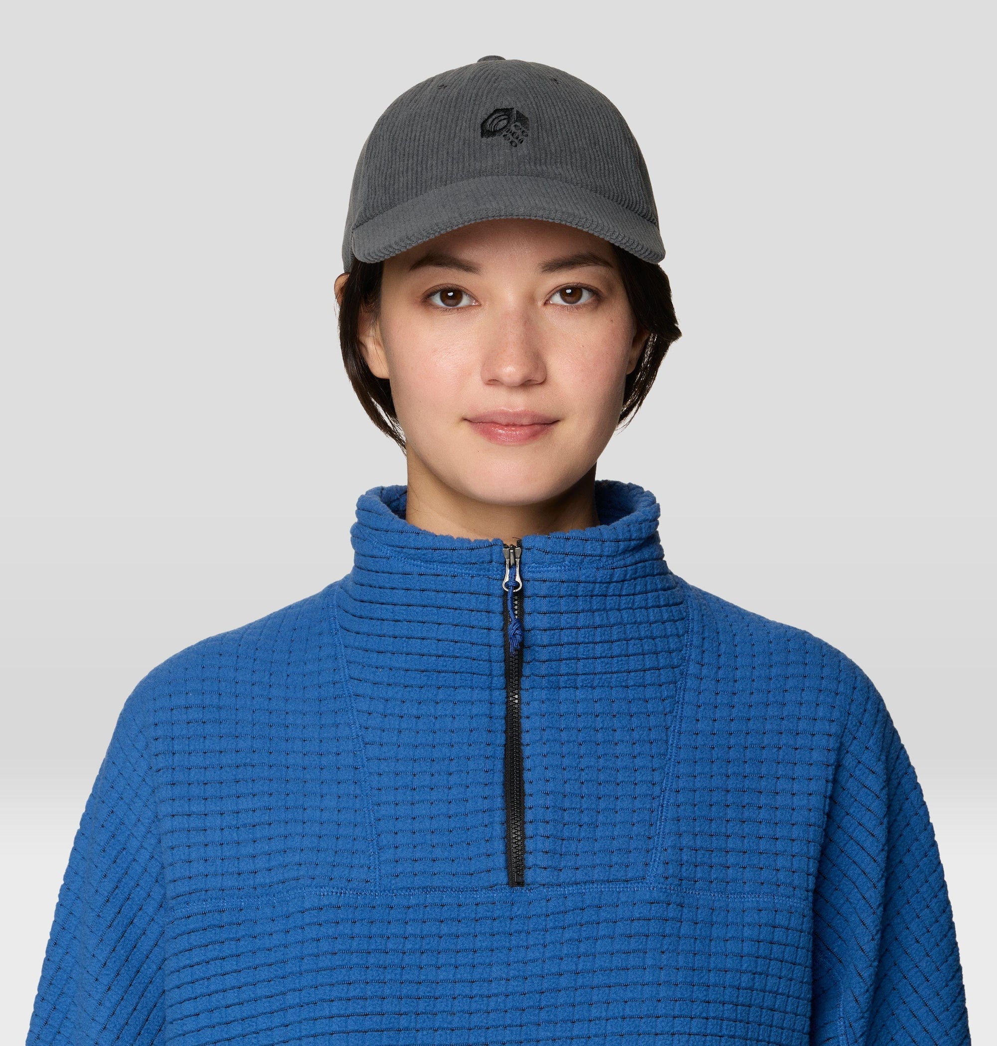 Dark gray corduroy dad cap with small logo, worn by model, front view