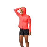 Woman wearing bright coral hooded running jacket with black patterned shorts, hand on forehead