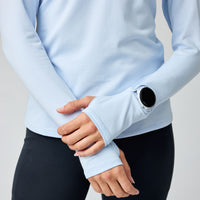 Light blue long-sleeve athletic top with thumb holes, lifestyle shot showing sleeve detail