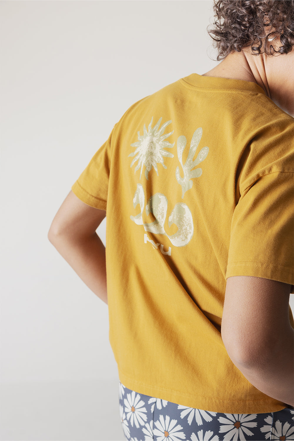 Yellow t-shirt with white botanical print on back, shown from behind on model