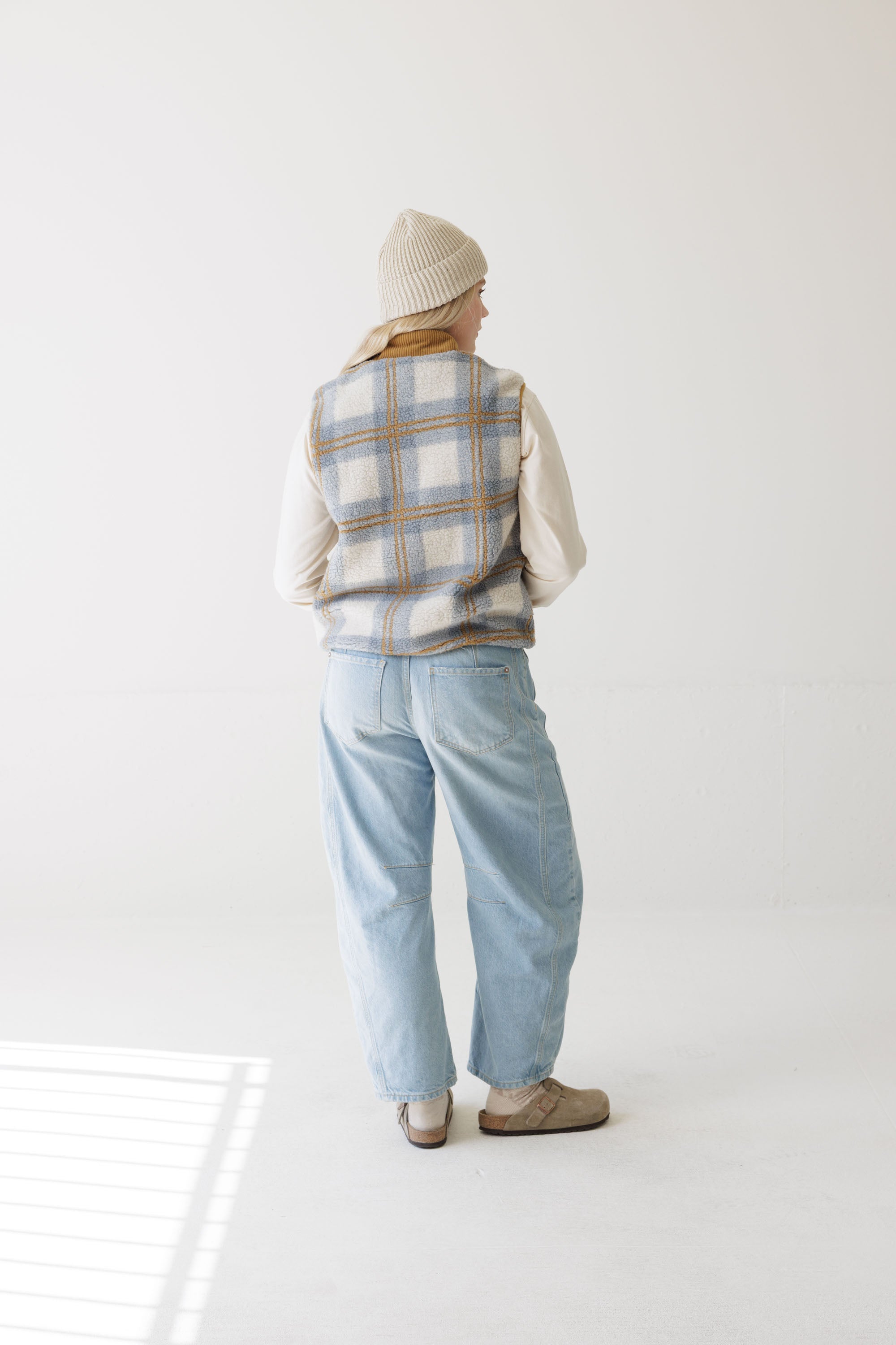 Women's plaid fleece vest, back view, worn over cream long-sleeve with light wash jeans