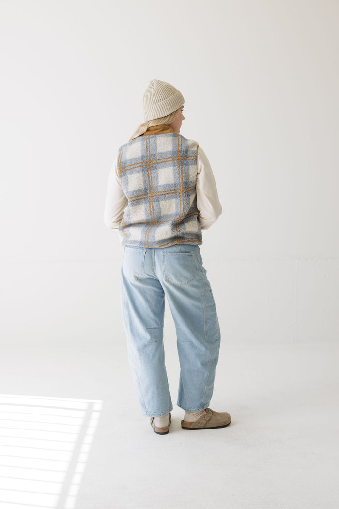 Women's plaid fleece vest, back view, worn over cream long-sleeve with light wash jeans