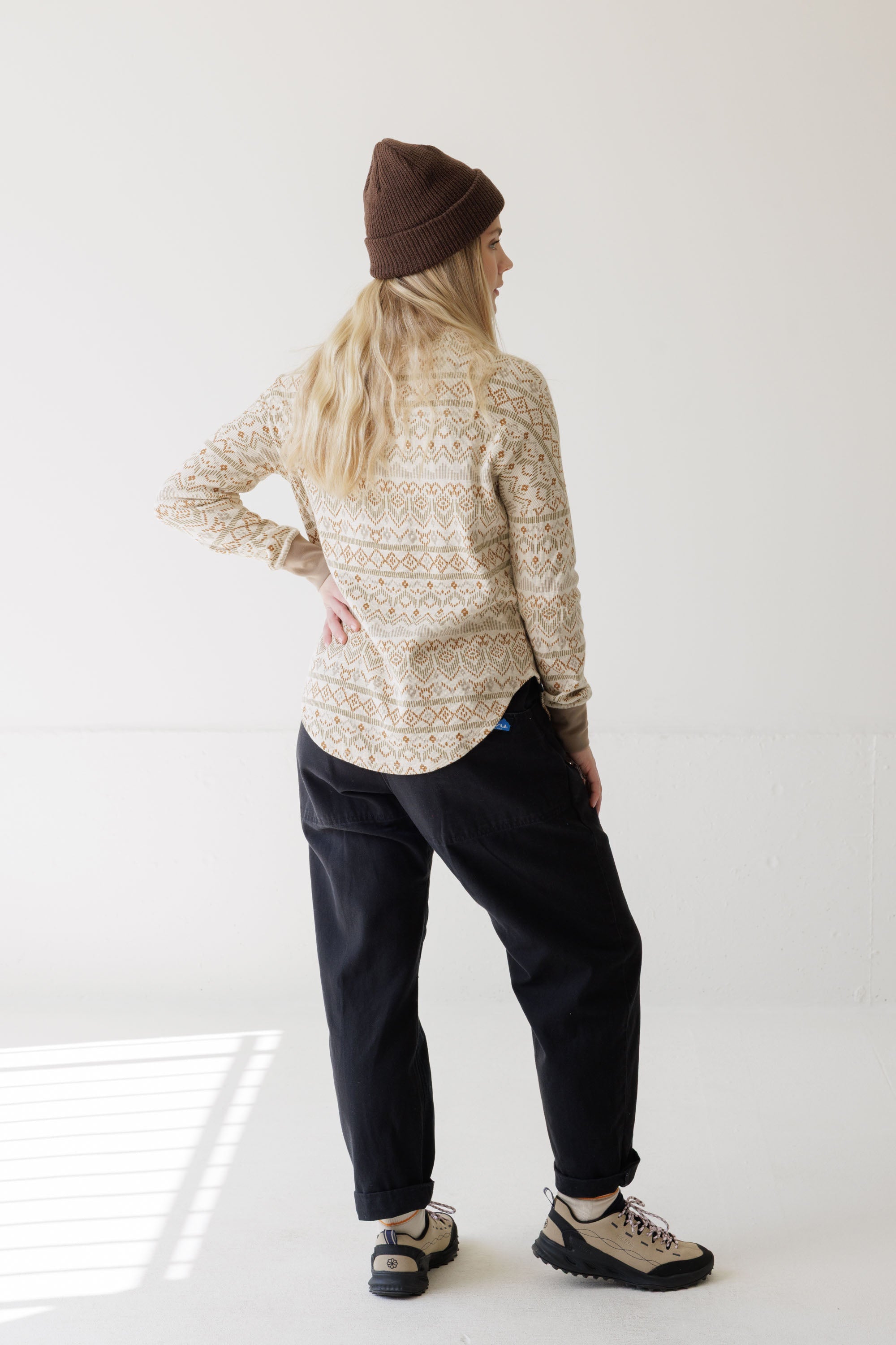 Women's patterned long-sleeve top with geometric print, back view, styled with dark pants and hiking shoes
