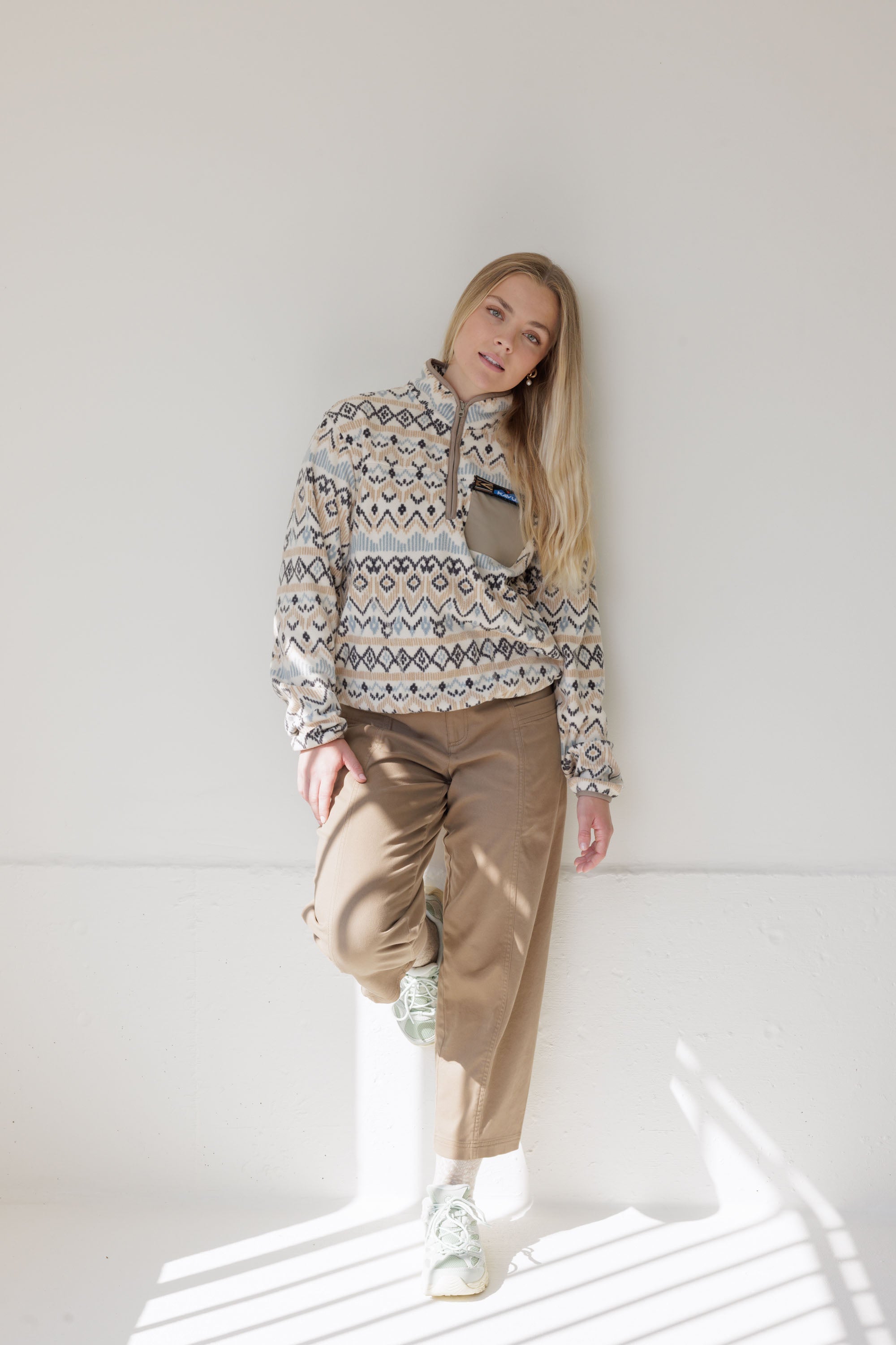 Women's patterned fleece pullover with half-zip, geometric print, paired with khaki trousers, front view