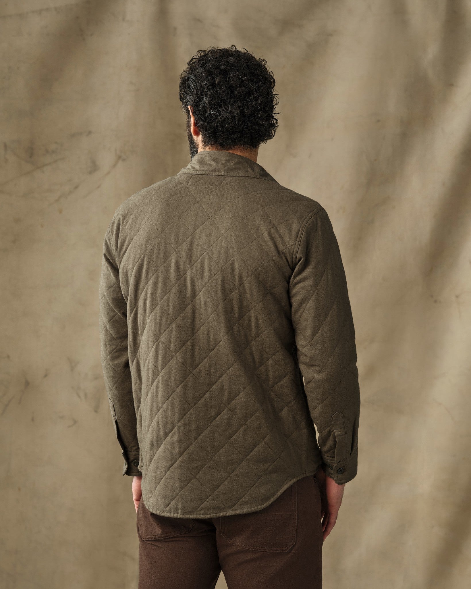 Back view of men's quilted olive green shirt jacket with diamond stitching pattern