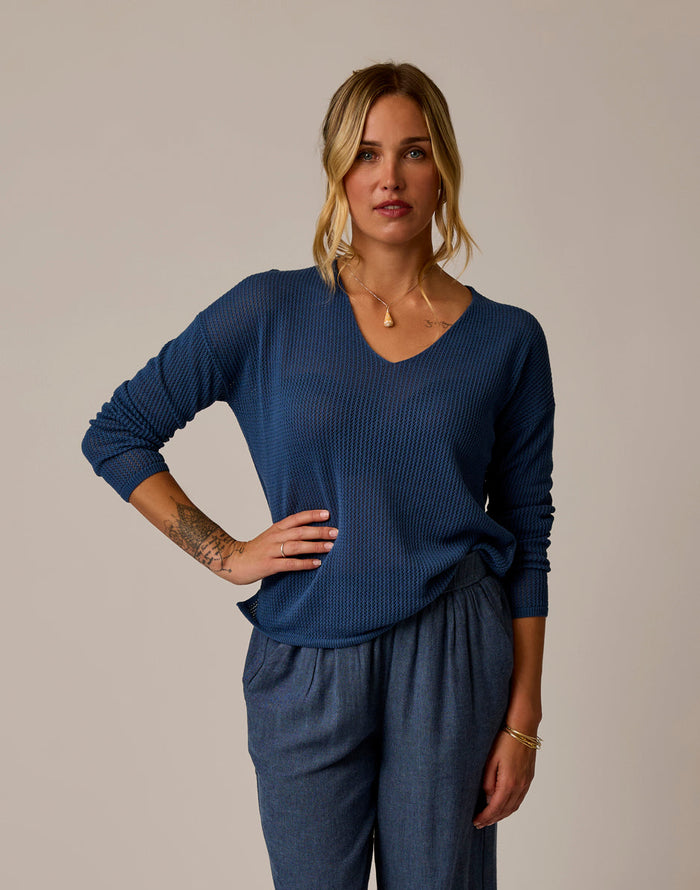 Woman wearing blue textured mesh pullover with v-neck and long sleeves