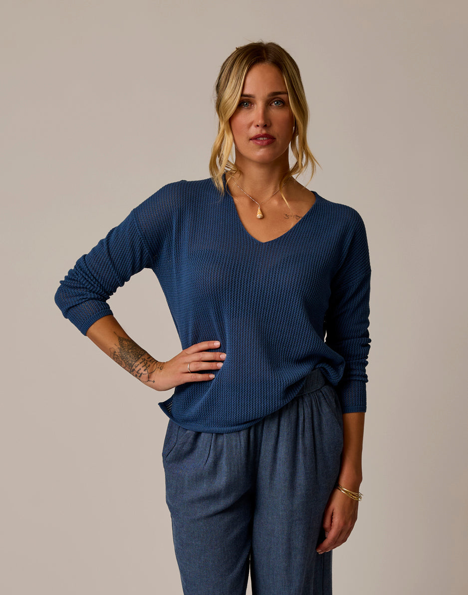Woman wearing blue textured mesh pullover with v-neck and long sleeves