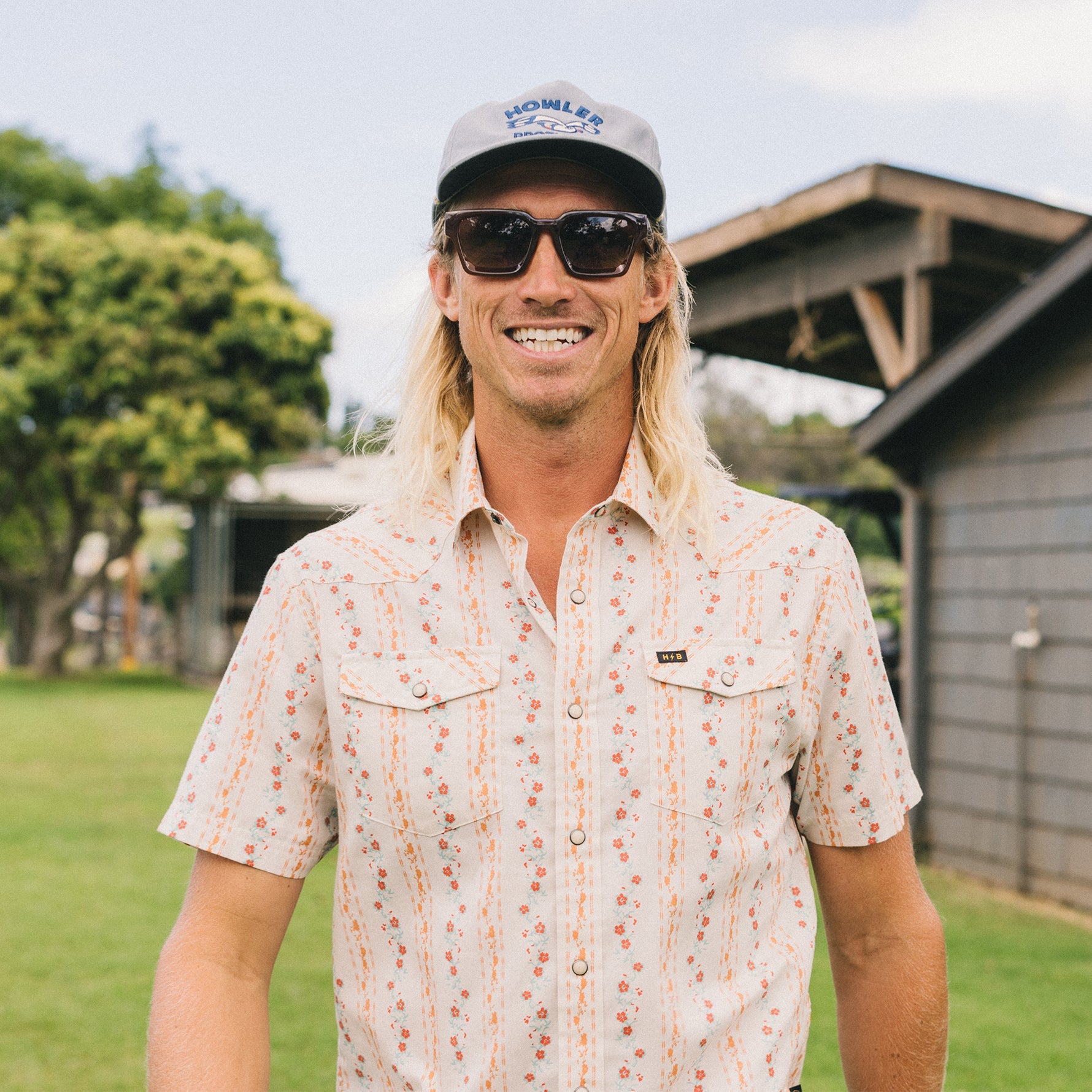 Man wearing a short-sleeve floral striped snap-button shirt, front view, outdoors