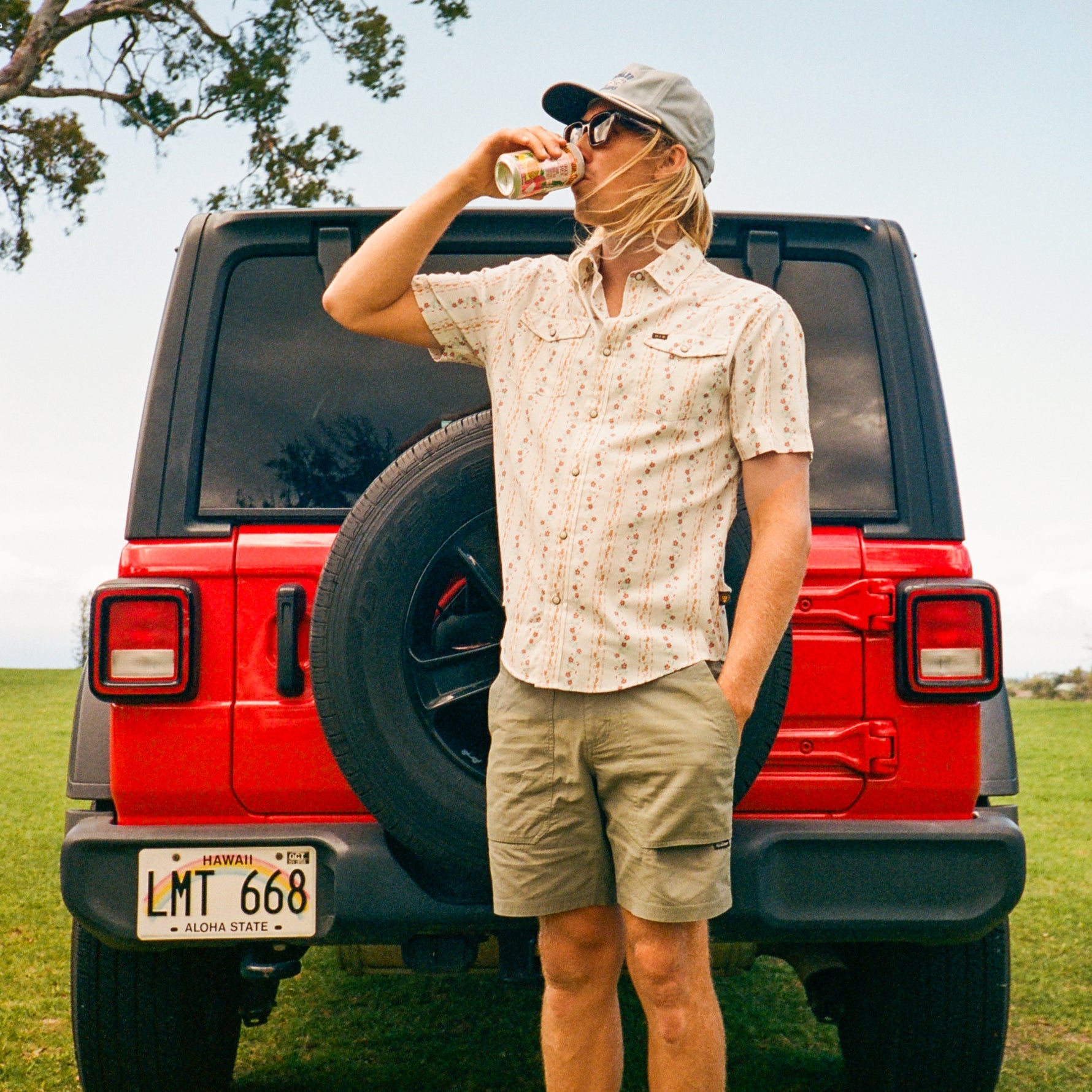 Men's short-sleeve snap button shirt with floral print, worn on model outdoors near red Jeep