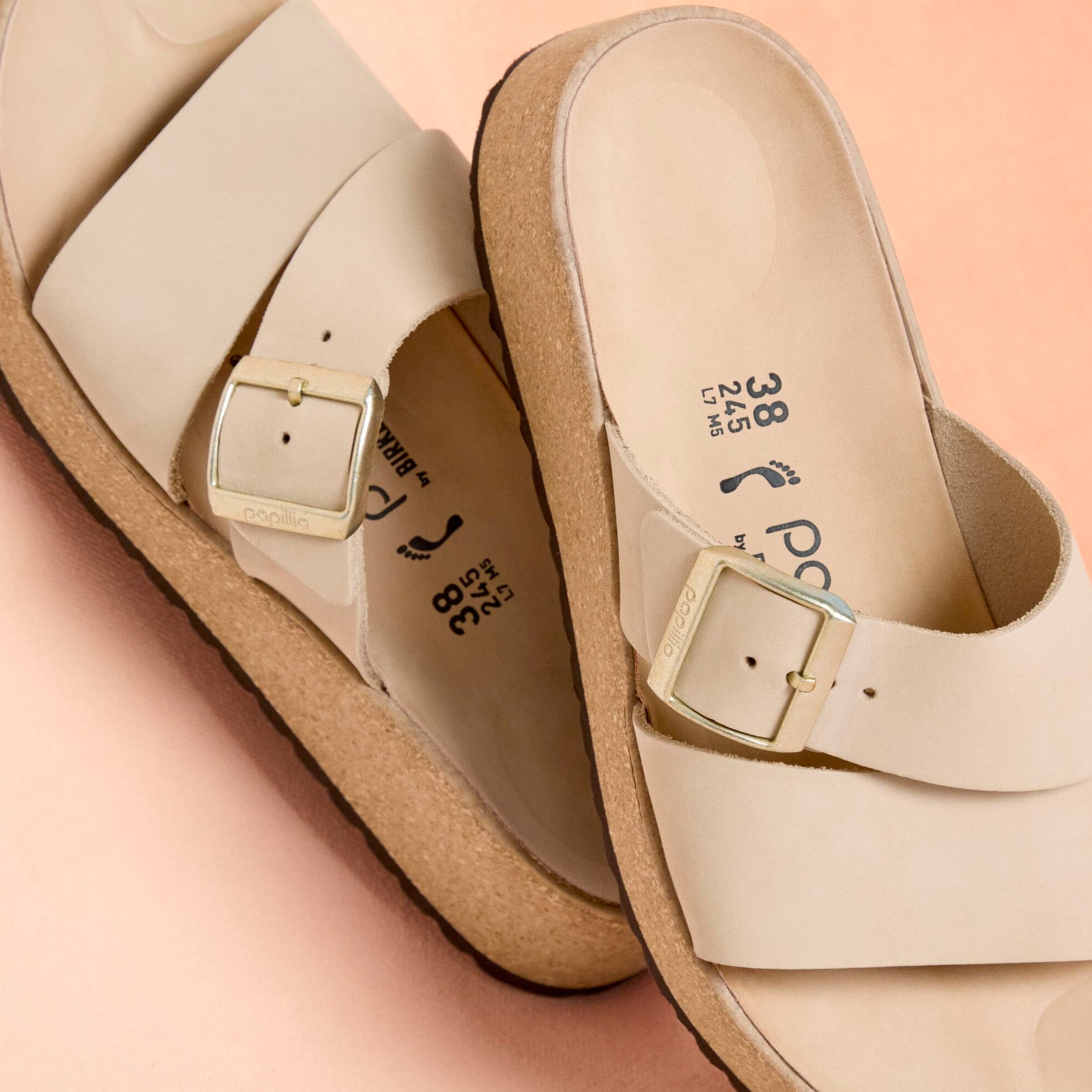 Light beige nubuck leather slide sandals with adjustable buckle straps and cork footbed