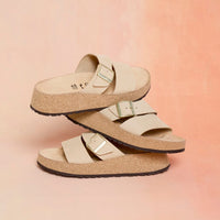 Light beige two-strap sandals with adjustable buckles and cork sole, stacked view