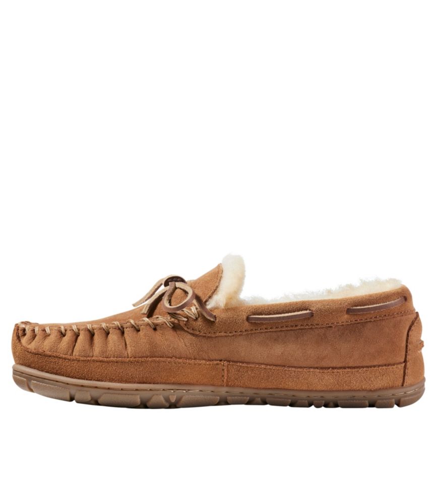 Brown suede moccasin slipper with shearling lining, leather lace tie, and rubber sole, side view
