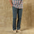 Dark blue-gray chino pants worn with plaid shirt and canvas sneakers, lower body view