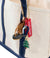 Miniature duck boot keychain with brown leather upper and dark sole, hanging from canvas tote
