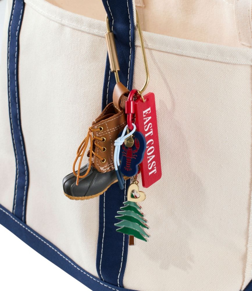 Miniature duck boot keychain with brown leather upper and dark sole, hanging from canvas tote