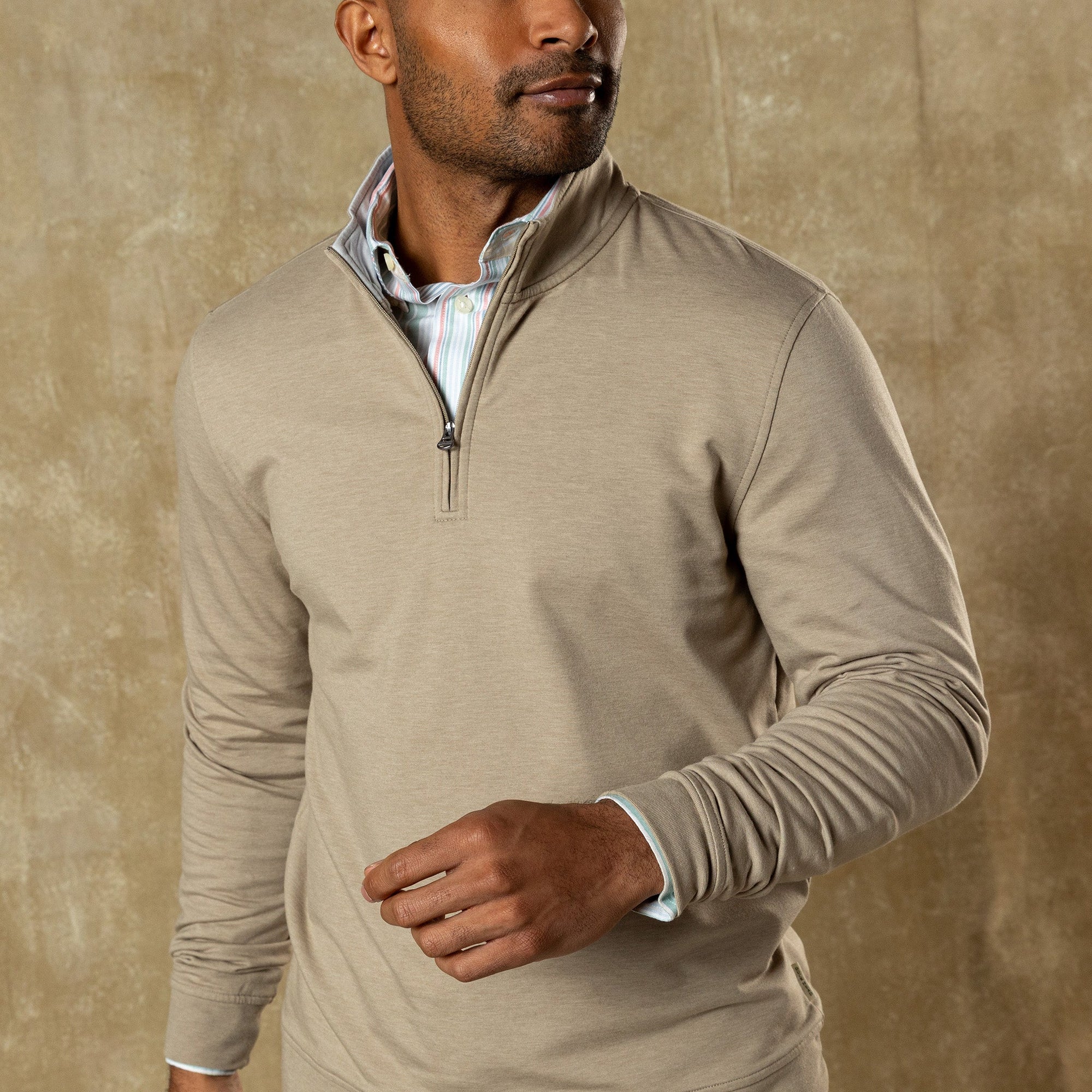 Man wearing light tan quarter-zip pullover over striped shirt, three-quarter view