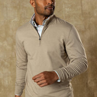 Man wearing light tan quarter-zip pullover over striped shirt, three-quarter view