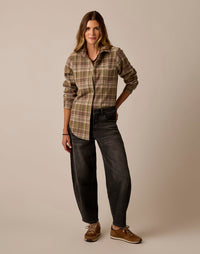 Women's plaid flannel button-up shirt in olive tones, full-length front view on model