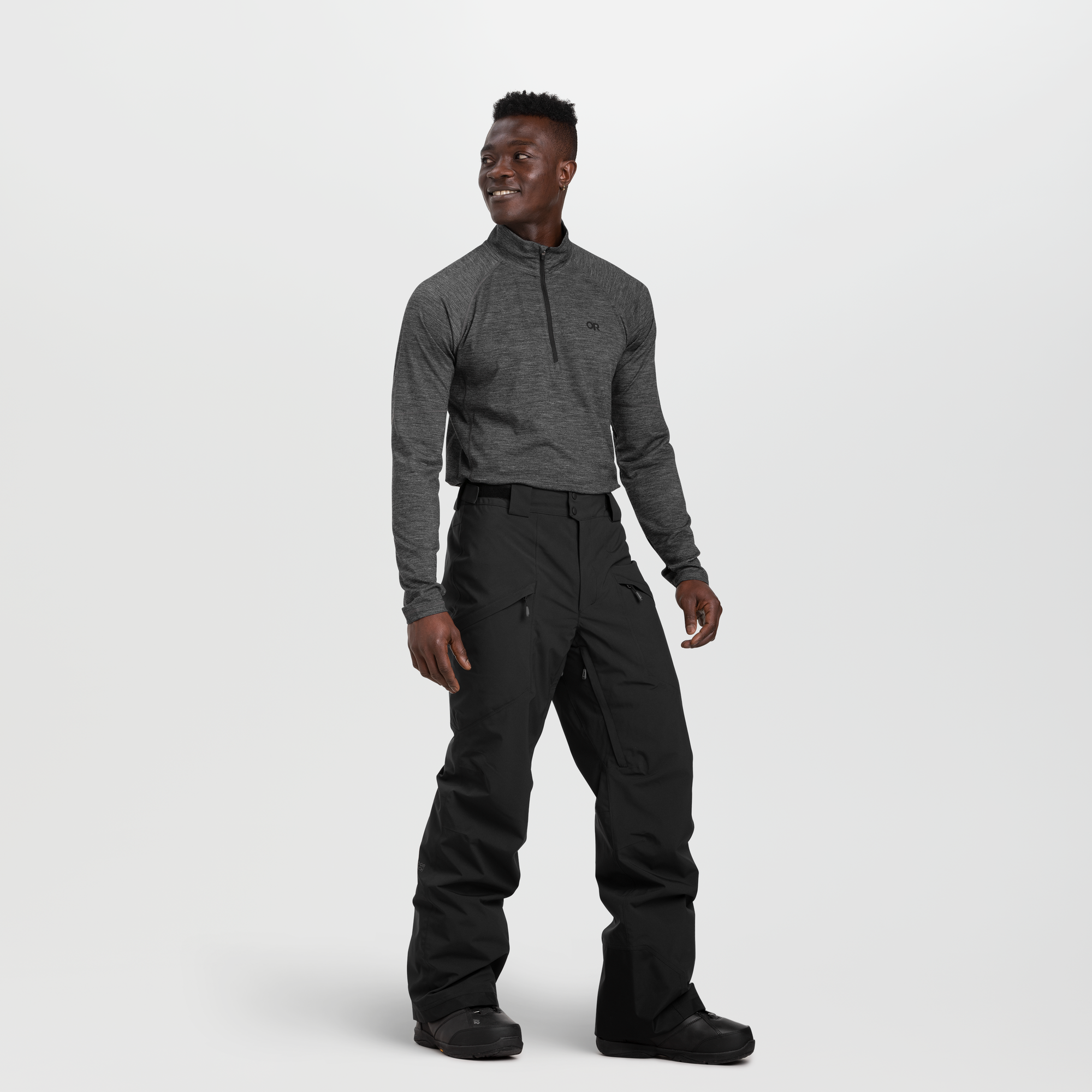 Men's black snow pants with multiple pockets, worn with gray base layer, front view