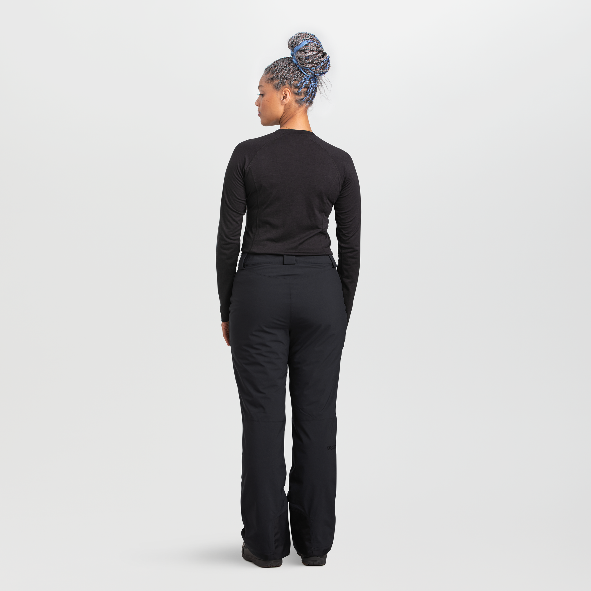 Women's black snow pants back view, relaxed fit with belt loops, worn with base layer top