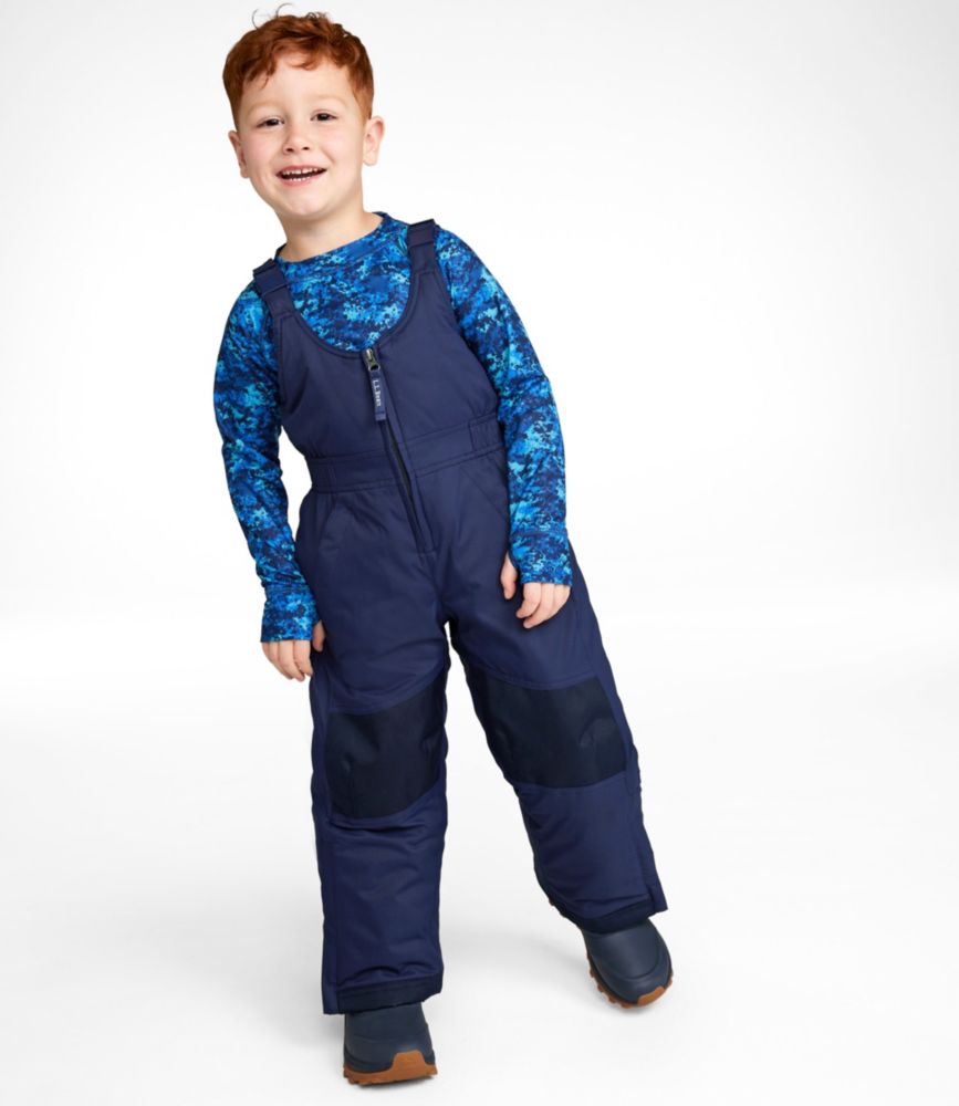 Child wearing navy insulated snow bib overalls with front zipper and reinforced knees, front view