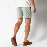 Light green chino shorts worn by model from behind, showing fit and length