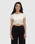Woman wearing cream colored short-sleeve crop top with twisted front detail and black pants