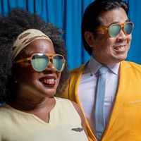 Two people wearing matching orange aviator sunglasses in lifestyle photo