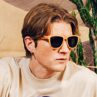 Orange sunglasses worn by person in cream shirt, outdoor lifestyle shot