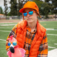 Blue mirrored sunglasses worn by person in orange outfit on sports field