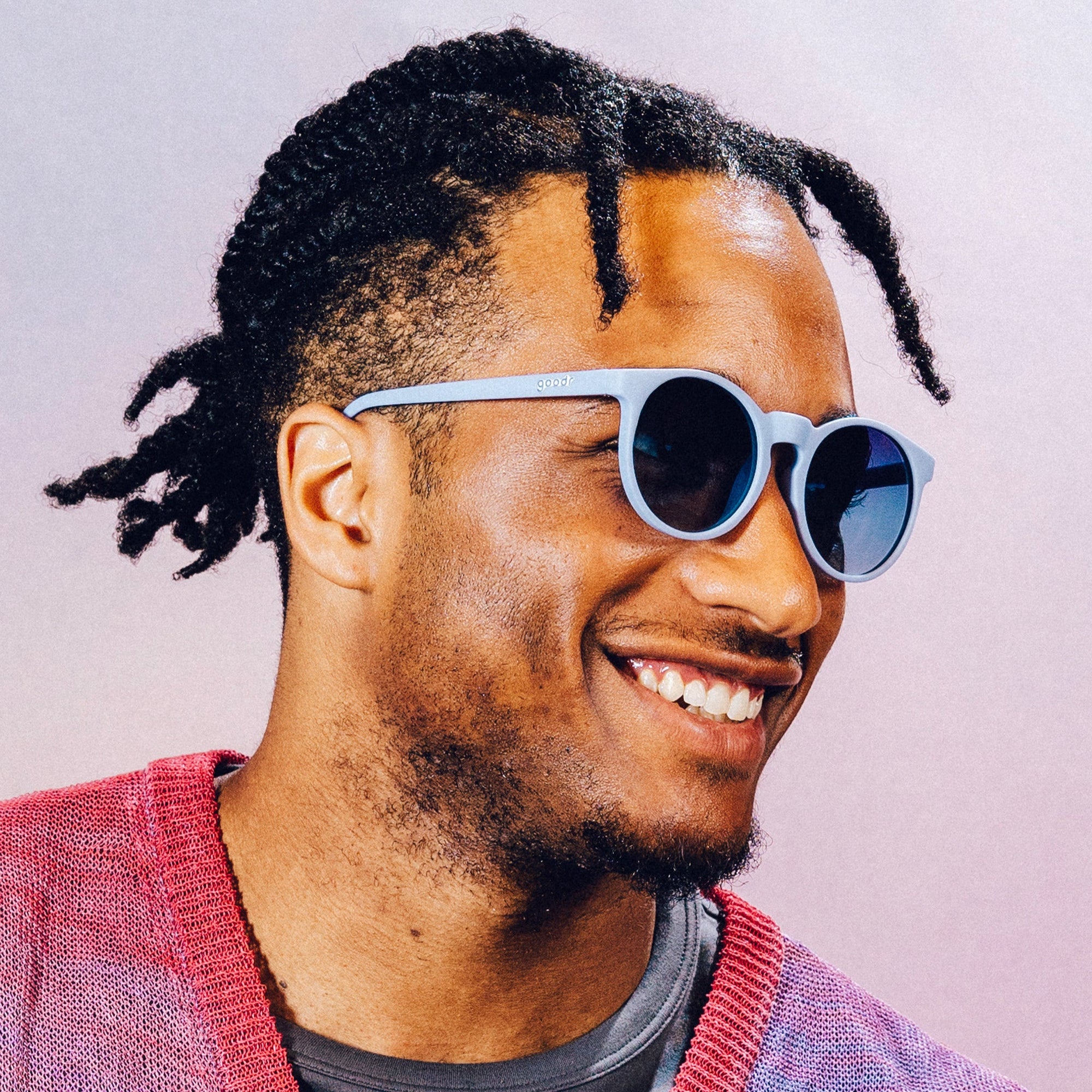 Light blue round sunglasses with dark lenses worn by smiling man in lifestyle photo