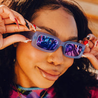 Woman wearing rectangular sunglasses with light blue frames and colorful mirrored lenses