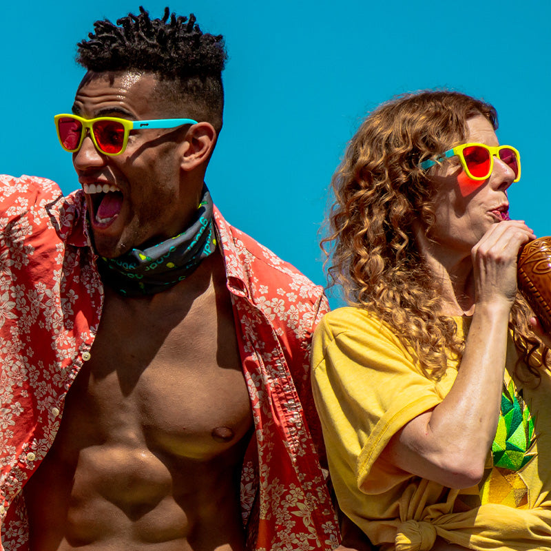 Colorful sunglasses with yellow and blue frames and orange reflective lenses worn by two people