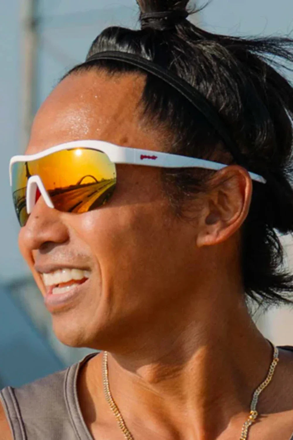 White wraparound sunglasses with orange mirrored lenses worn by smiling woman outdoors