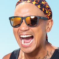 Dark frame sunglasses with orange reflective lenses worn by smiling person outdoors