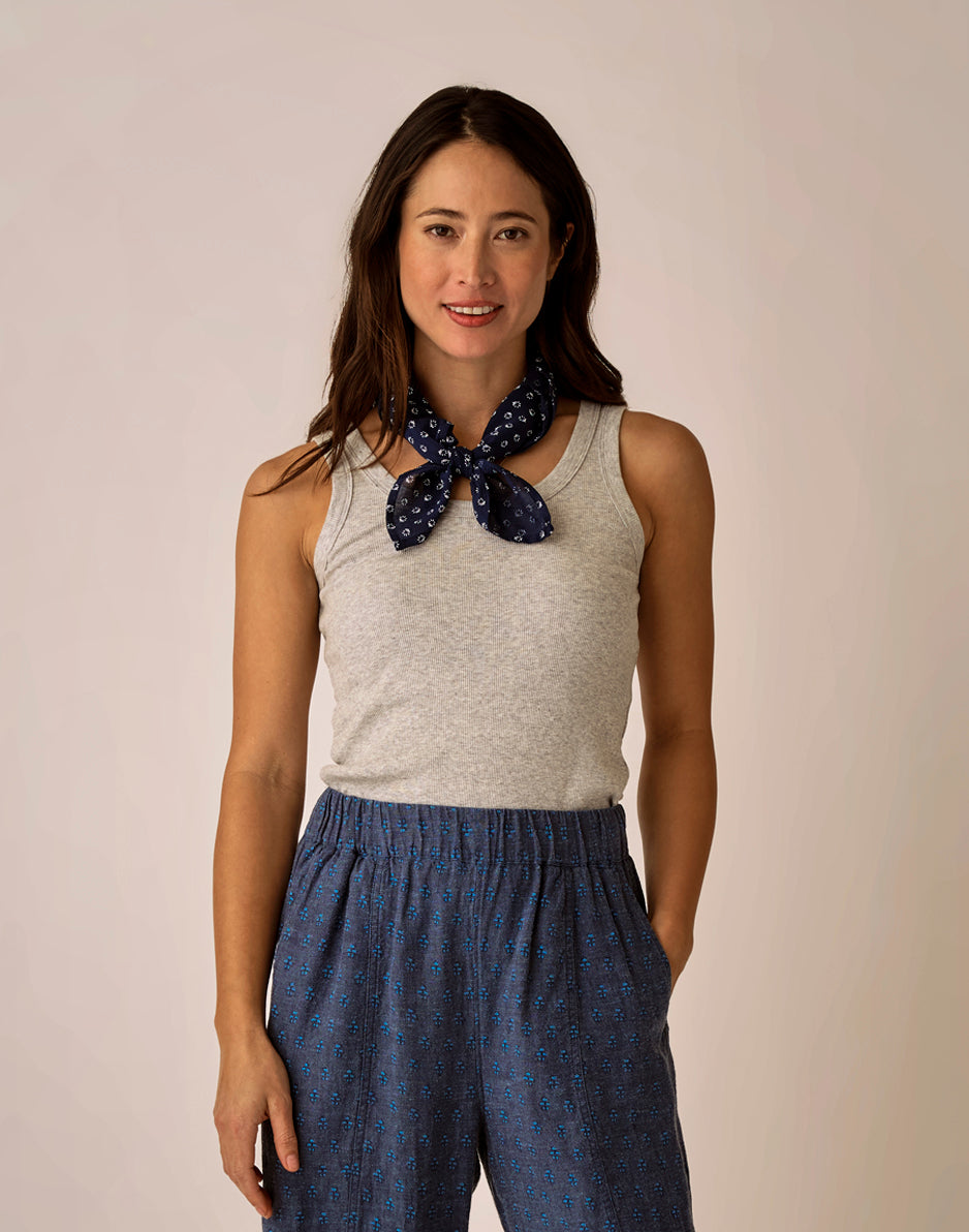 Light grey ribbed sleeveless tank top worn with blue patterned pants and neck scarf