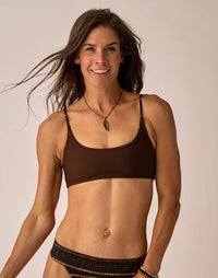 Women's dark brown reversible compression bikini top with thin patterned straps, front view on model