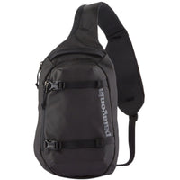 Black sling bag with single shoulder strap, front zipper pocket, and buckle straps, angled view
