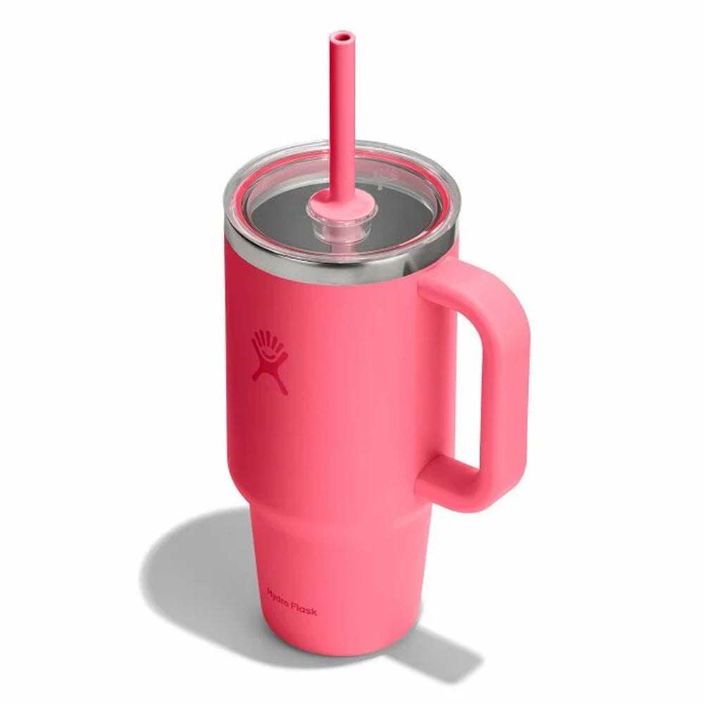 Coral pink insulated travel tumbler with handle, clear lid, and matching straw, angled view