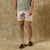 Light pink chino shorts worn with green t-shirt and brown boat shoes, studio shot
